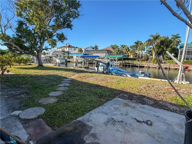 Dock featuring boat lift, a yard, and a water view