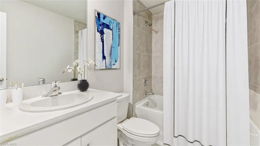 Full bathroom featuring tiled shower / bath combo, vanity, and toilet