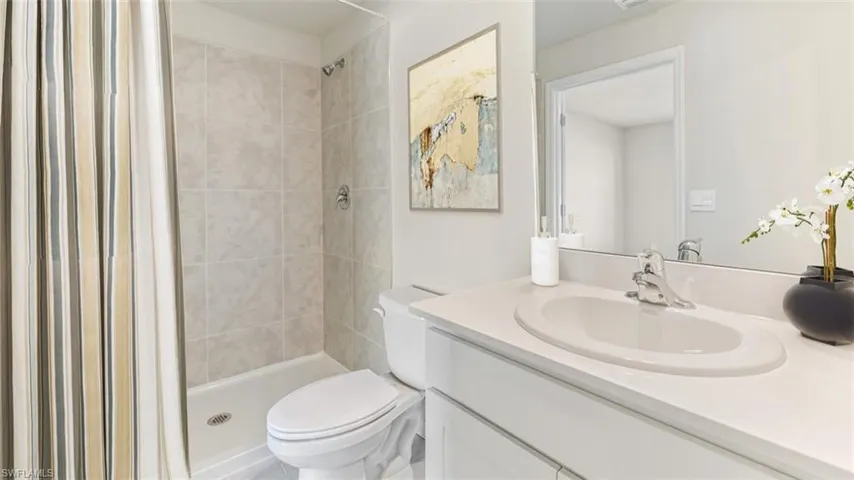 Bathroom featuring toilet, a tile shower, and vanity