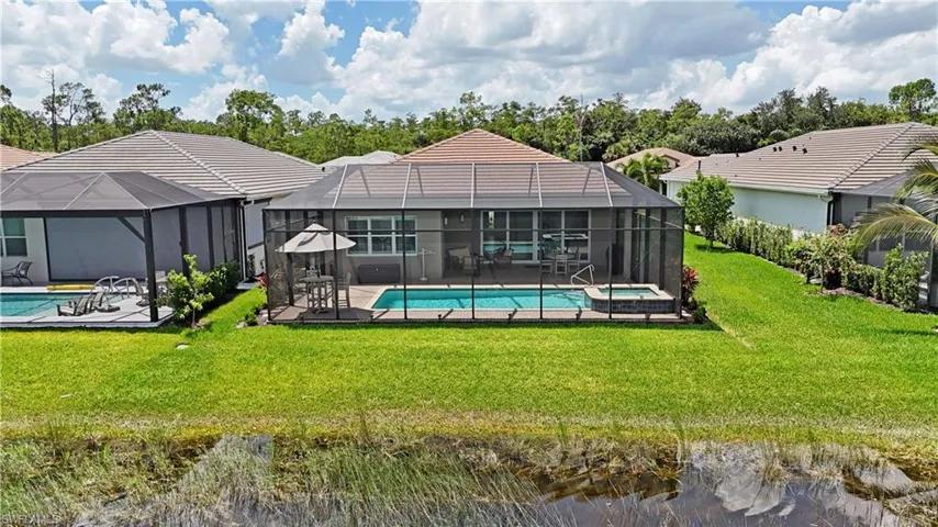Back of property featuring a lawn, a patio area, and a lanai
