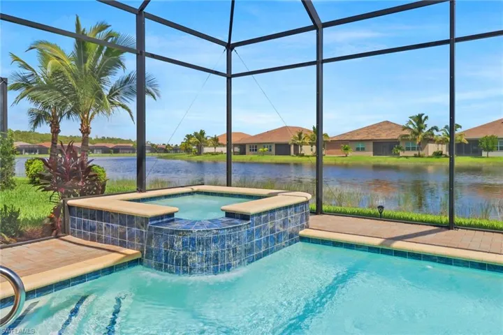View of pool with an in ground hot tub and glass enclosure