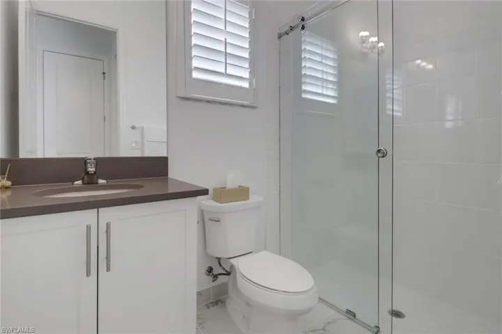 Bathroom featuring tile patterned flooring, vanity, walk in shower, and toilet