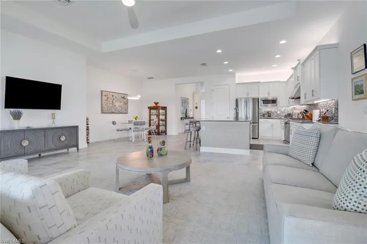 Living room with ceiling fan, a raised ceiling, and light tile patterned flooring