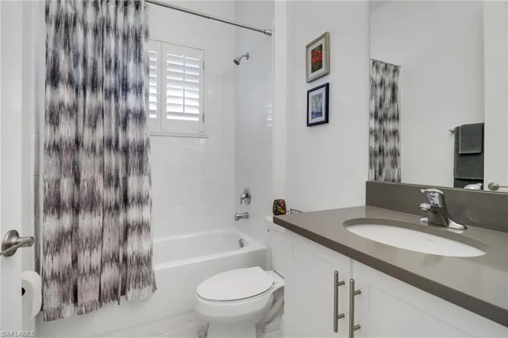 Full bathroom featuring shower / bath combination with curtain, toilet, and vanity