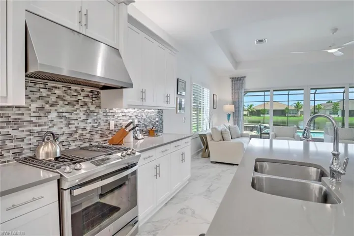 Kitchen featuring ceiling fan, tasteful backsplash, stainless steel gas stove, light tile patterned floors, and sink
