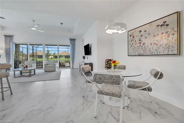 Dining area with ceiling fan, a raised ceiling, and light tile patterned floors