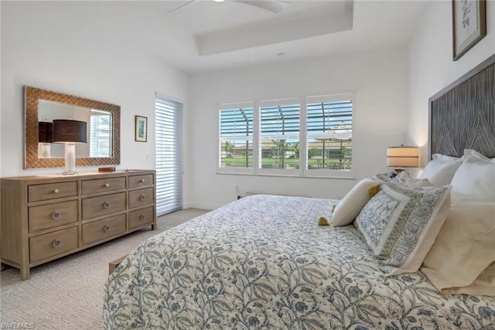 Bedroom with a tray ceiling, ceiling fan, and light colored carpet