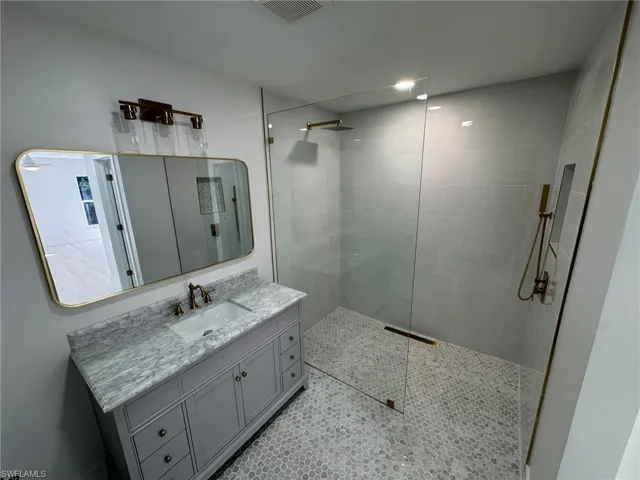 Bathroom featuring a walk in shower and vanity