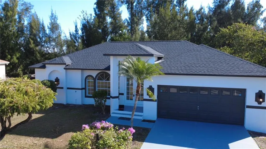 View of front of house featuring roof with shingles, stucco siding, concrete driveway, and a garage