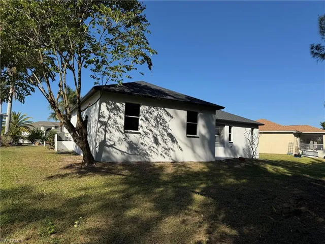Rear view of house featuring a yard and stucco siding