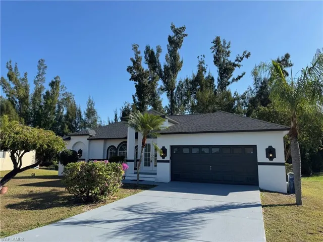 View of front facade featuring a front yard, stucco siding, concrete driveway, and an attached garage