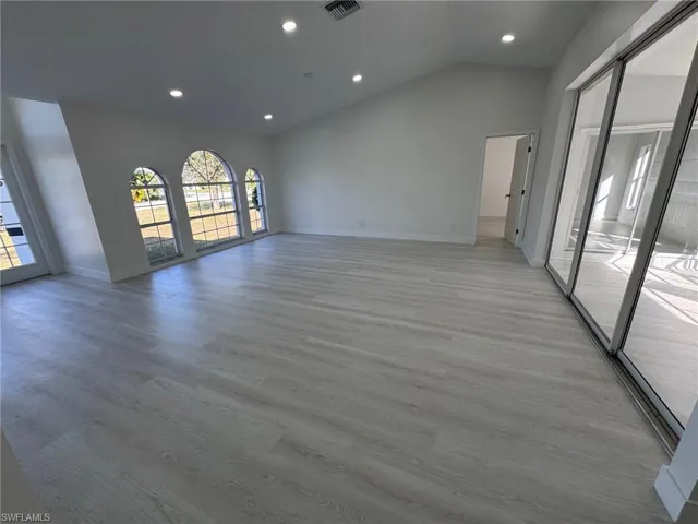 Unfurnished room with vaulted ceiling, light wood-style floors, and recessed lighting