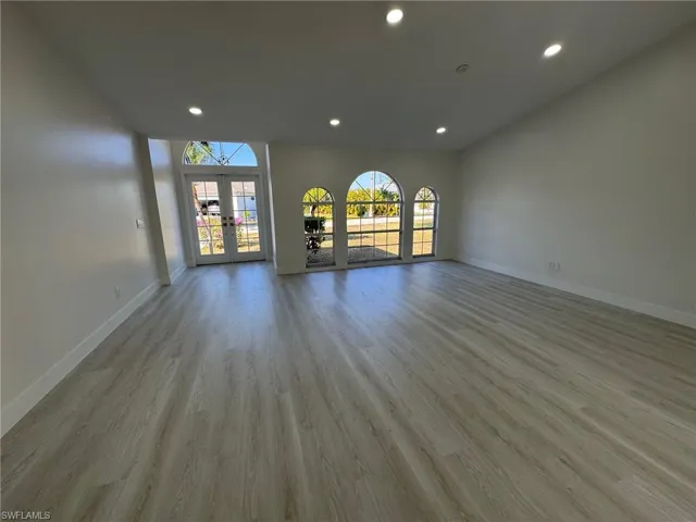 Unfurnished living room featuring light wood-style flooring, recessed lighting, and french doors