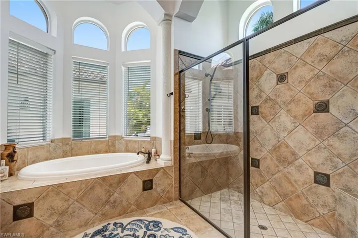 Full bathroom featuring a stall shower, a bath, decorative columns, and tile patterned flooring