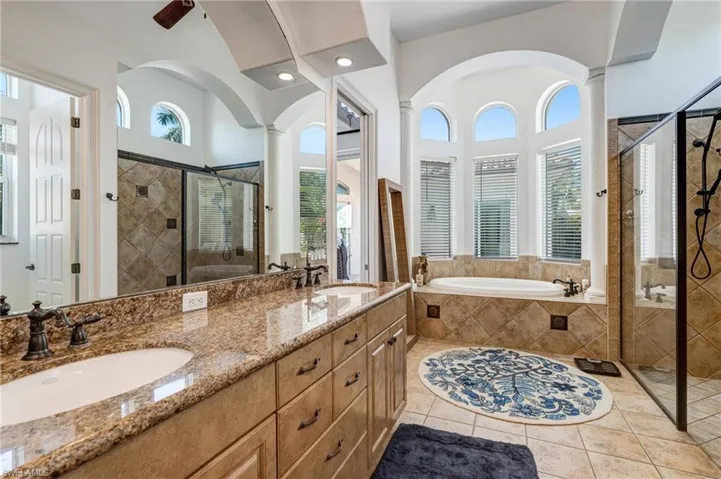 Bathroom with a shower stall, a garden tub, double vanity, and light tile patterned floors