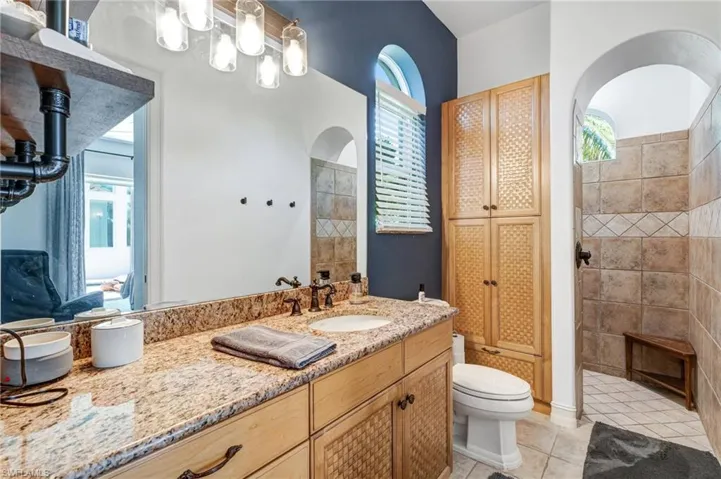 Bathroom featuring light tile patterned flooring, vanity, a tile shower, and a closet
