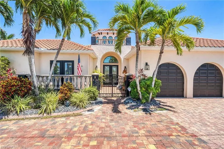 Mediterranean / spanish-style house featuring a garage, a gate, decorative driveway, a tile roof, and french doors