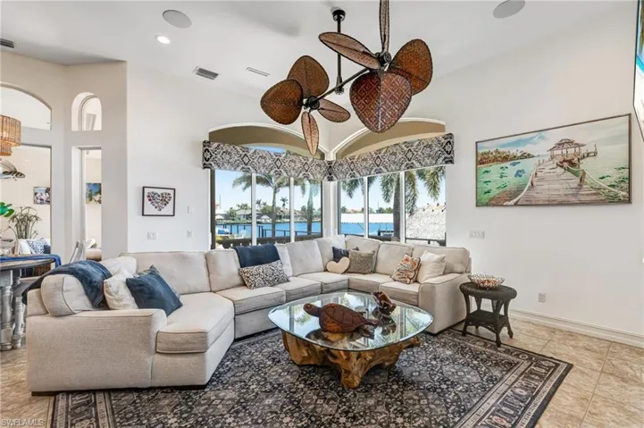 Living room featuring light tile patterned flooring, a water view, a high ceiling, recessed lighting, and ceiling fan