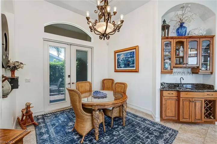 Dining area with a chandelier, light tile patterned floors, and wet bar