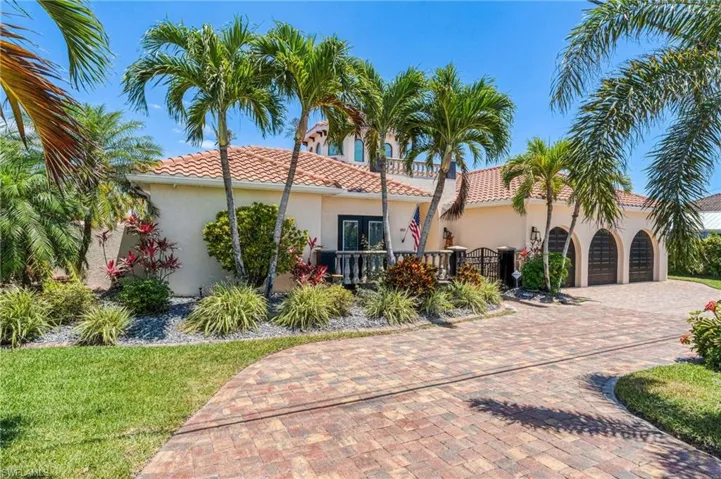 Mediterranean / spanish-style house with a garage, stucco siding, a tile roof, decorative driveway, and a front lawn