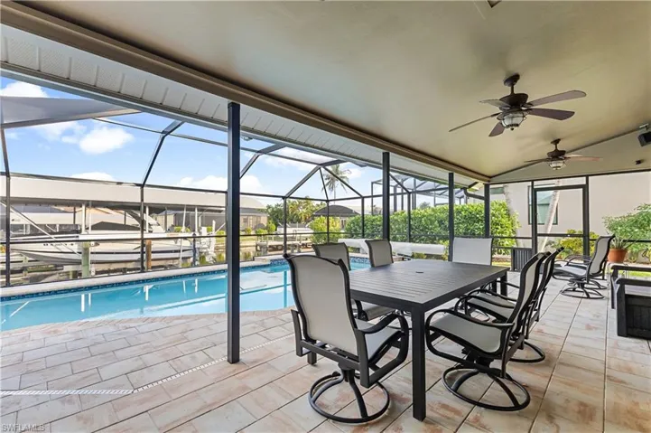 View of pool featuring a lanai, ceiling fan, and a covered seating area
