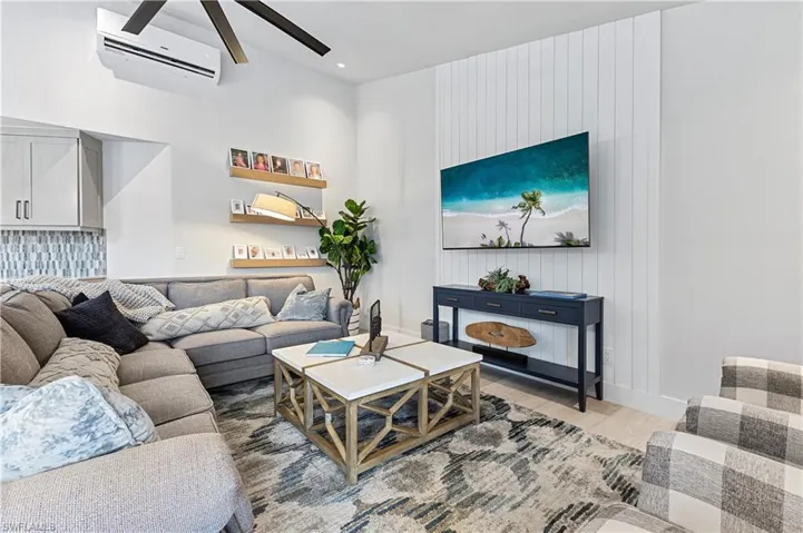 Living room featuring wood-type flooring, a wall unit AC, and ceiling fan