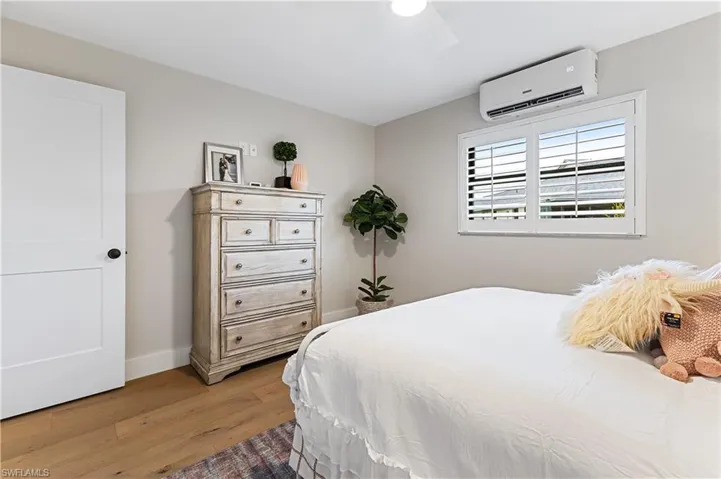 Bedroom featuring ceiling fan, wood floors, and a wall mounted AC