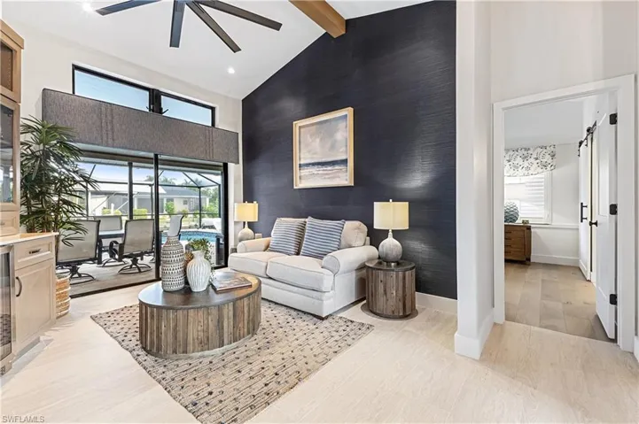 Living room with high vaulted ceiling, ceiling fan, and plenty of natural light