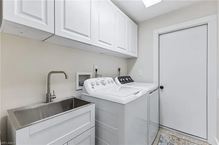 Laundry room featuring sink, washing machine and clothes dryer, and cabinets