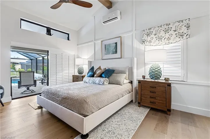 Bedroom featuring ceiling fan, a wall mounted AC, high vaulted ceiling, genuine wood-style flooring, and access to exterior through sliders