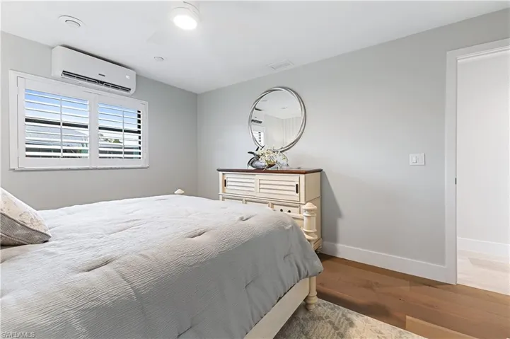 Bedroom with wood flooring, ceiling fan, and an AC wall unit