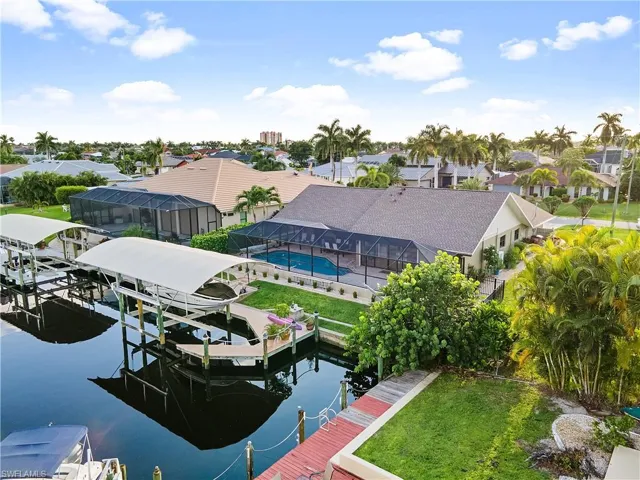 Back of House Showcasing the 20,000 LB Lift & Canopy, Pool, Screened Lanai, and Direct Gulf Access Canal