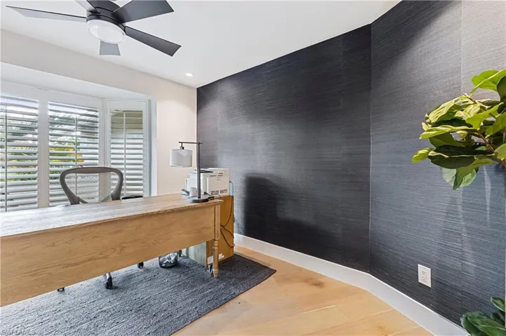 Office area with ceiling fan and wood flooring