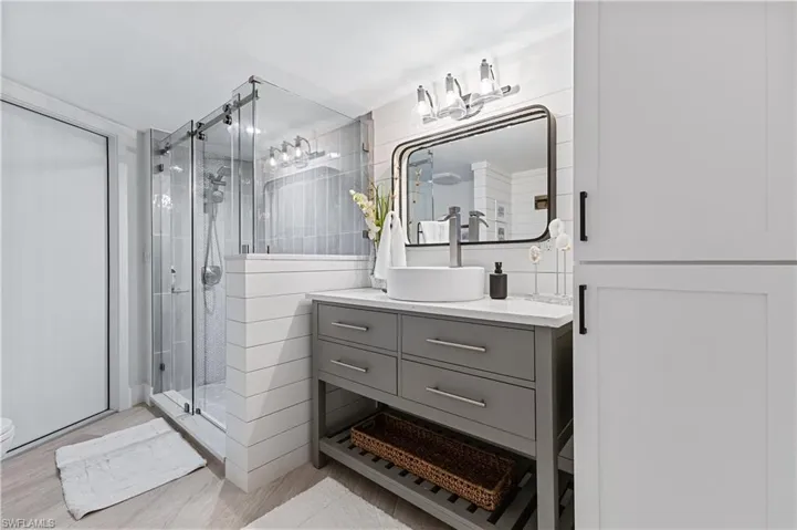 Bathroom featuring tile walls, an enclosed shower, and stylish vanity
