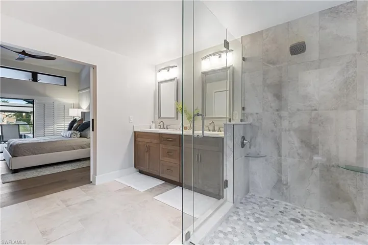 Bathroom featuring tiled shower, vanity, and tile floors