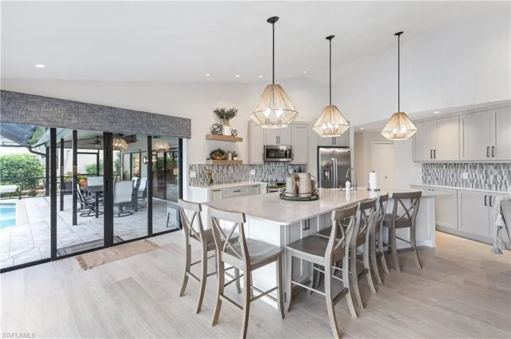 Dining area with light hardwood / wood-style floors, lofted ceiling, an inviting chandelier, and sink