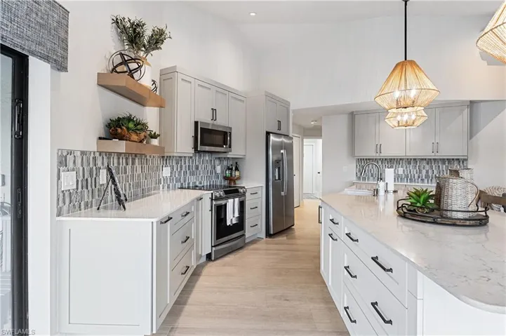 Kitchen featuring decorative backsplash, stainless steel appliances, light hardwood / wood-style flooring, sink, and a notable chandelier