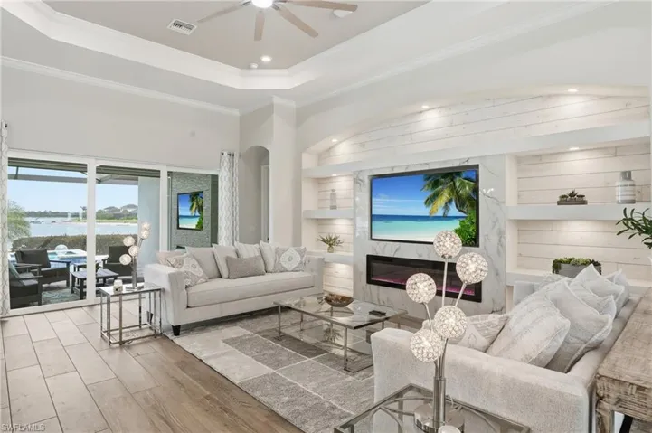 Living area featuring wood-finish flooring, a tray ceiling with a fan, and crown molding