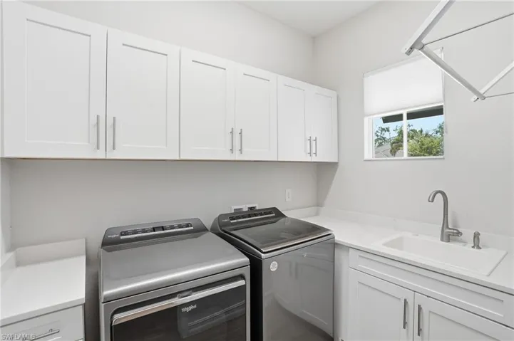 Laundry room featuring white shaker cabinetry, light countertops, a utility sink with a gooseneck faucet, and a window with natural light