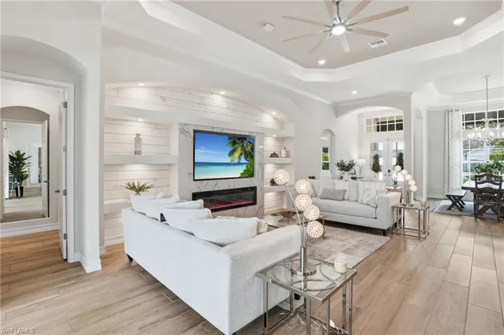 Spacious living area featuring light wood-finish flooring and a built-in media center with shiplap-style paneling and accent lighting