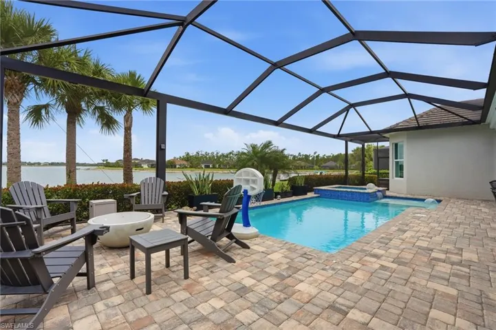 Screened outdoor living area featuring a rectangular pool and integrated spa