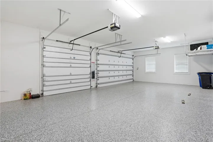 Spacious two-car garage featuring a speckled epoxy floor coating, two overhead garage door openers, and two windows