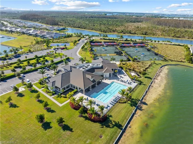 Community clubhouse featuring a swimming pool with surrounding lounge areas, extensive tennis courts, and ample parking