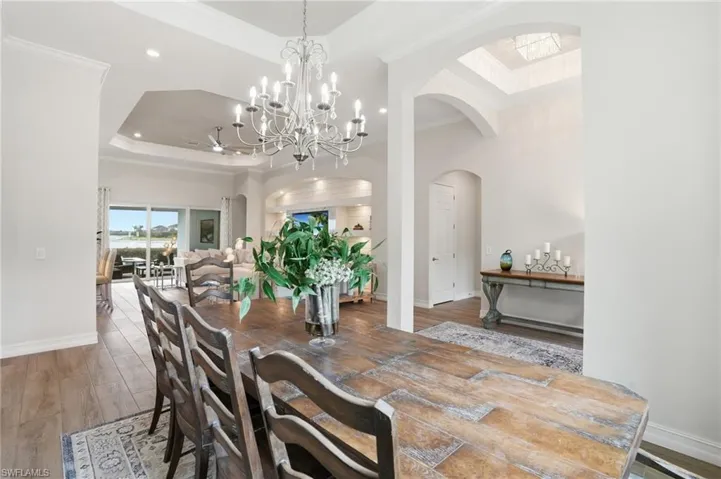 Spacious interior featuring wood-finish flooring, a tray ceiling, and an ornate chandelier