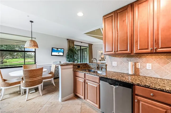 Kitchen with dark stone counters, dishwasher, pendant lighting, and sink