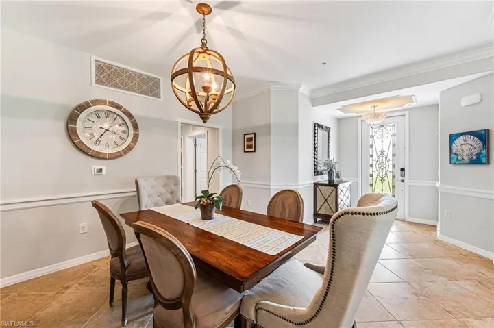 Tiled dining area featuring a notable chandelier and crown molding