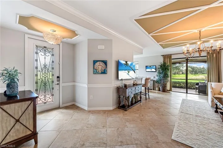 Entrance foyer with an inviting chandelier, light tile patterned floors, and crown molding