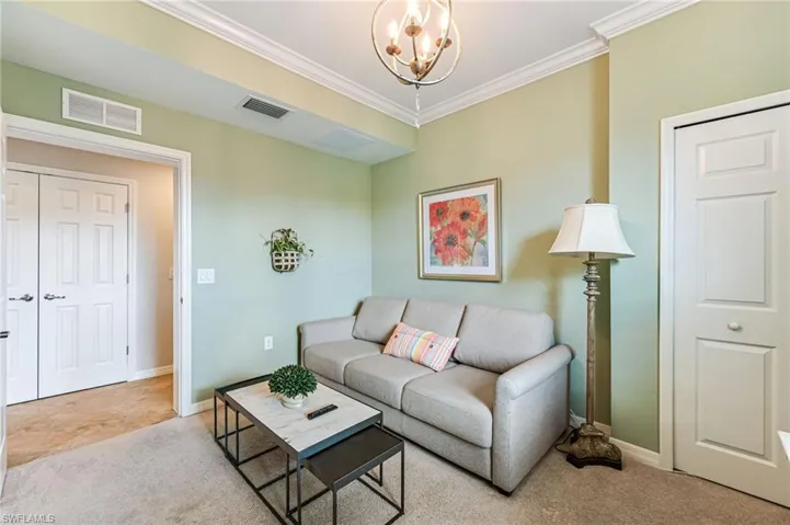 Carpeted living room featuring a notable chandelier and crown molding