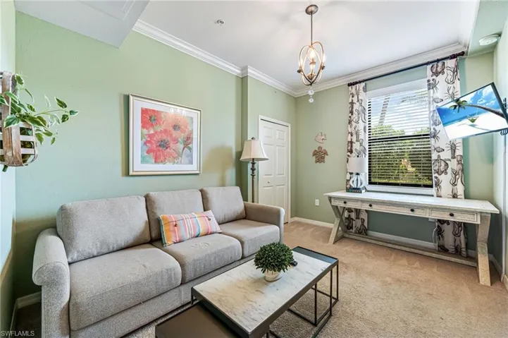 Living room featuring crown molding, an inviting chandelier, and light colored carpet