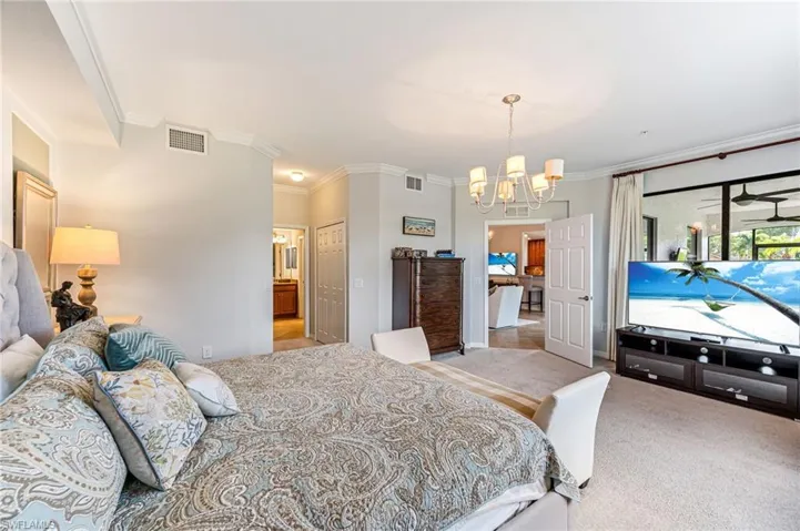 Bedroom with ornamental molding, light carpet, a closet, and an inviting chandelier